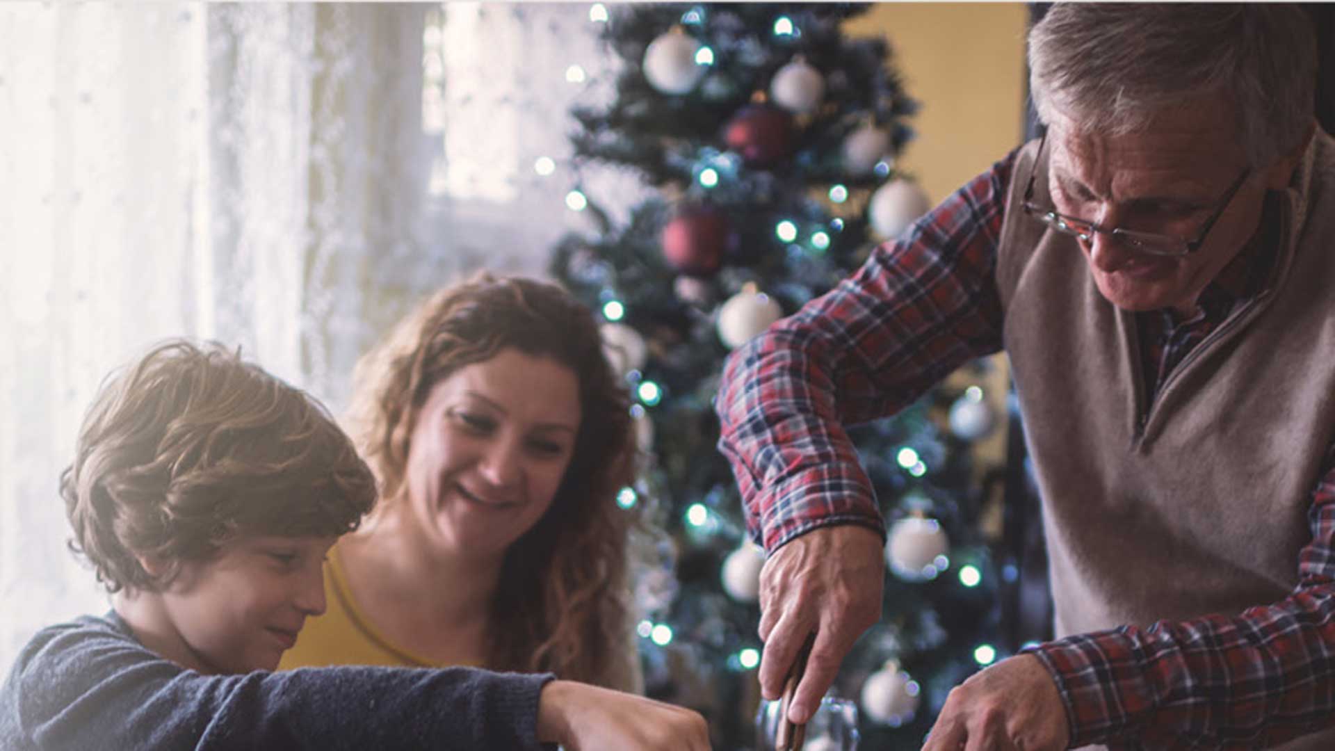 a man prepares a holiday turkey while his family members joyfully watch and converse