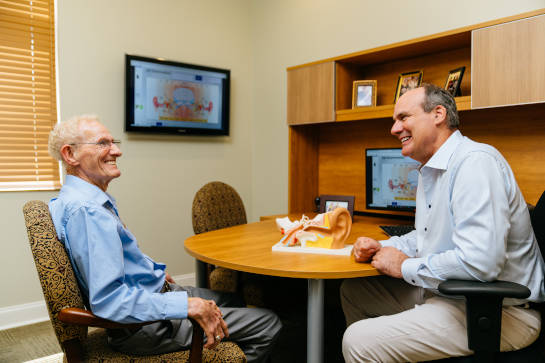 Dr. Tony Milliano explains hearing loss to an older male patient