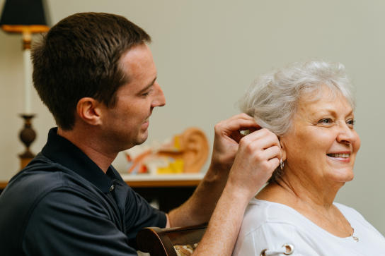 Dr. Jared Anderson fits an older female patient with hearing aids